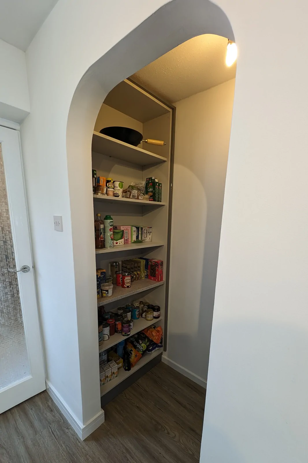 Built-in walk-in pantry with full-depth shelves for storing dry goods and appliances.