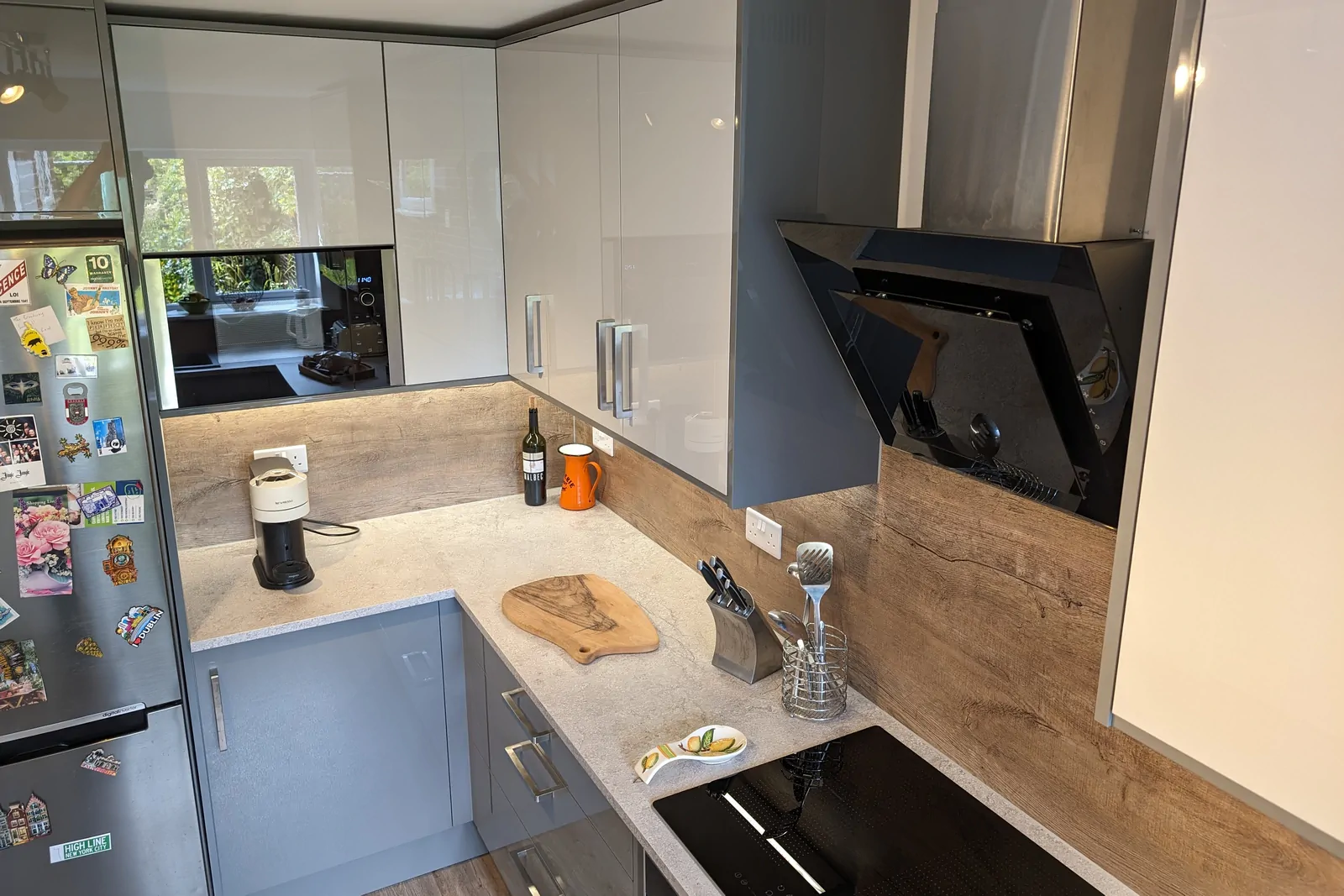 Calais Travertine laminate worktop meets an oak-effect full-height splashback with warm grain and character.