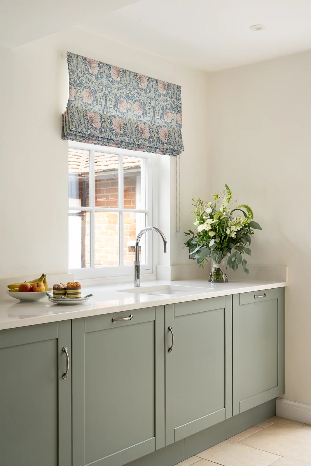 Sink area in a reed green shaker kitchen with white undermount sink, chrome Quooker tap, and seamless quartz worktop by Redwood Kitchens, Wokingham.