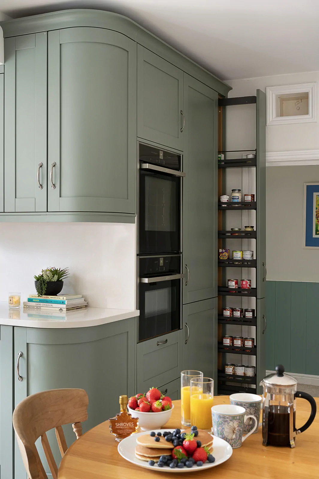 Reed green shaker kitchen with pull-out larder, Neff double ovens, and Silestone worktop by Redwood Kitchens, Wokingham.
