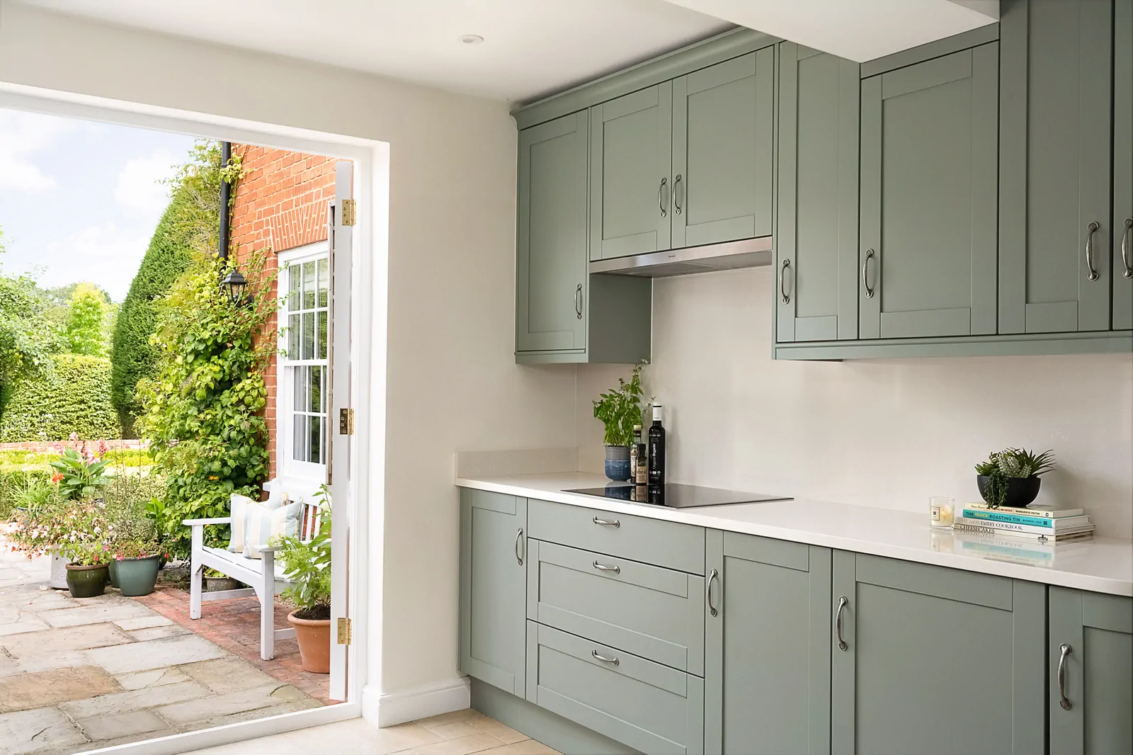 Reed green shaker kitchen in Binfield with Neff induction hob and pull-out canopy hood set against a seamless Silestone splashback by Redwood Kitchens, Wokingham