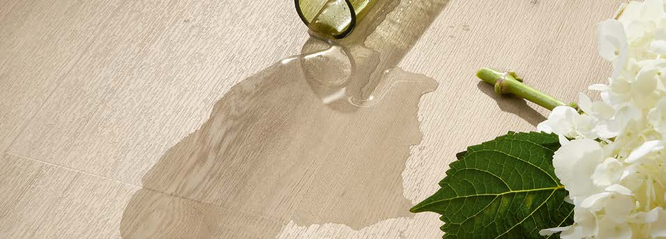 Knocked-over vase with spilt water and white flowers on a light LVT floor