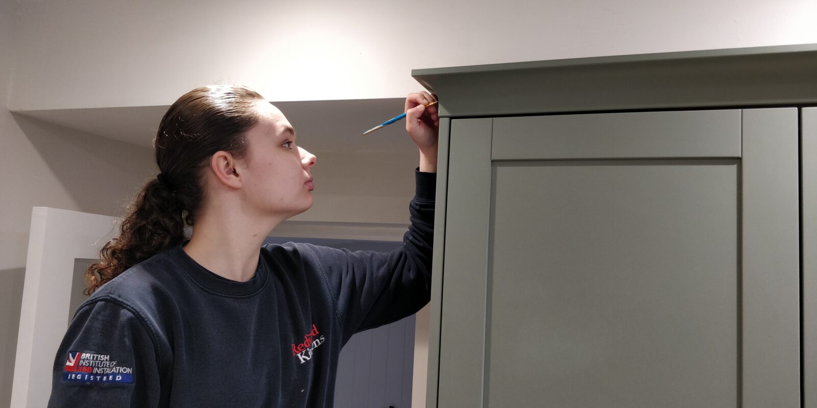 Touch-up paint being applied to a painted kitchen door with a fine brush